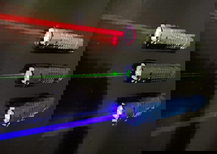 A group of dancers perform on a dark stage with purple and blue lighting. The image has a digital glitch effect, creating horizontal blue and purple lines across the lower half.